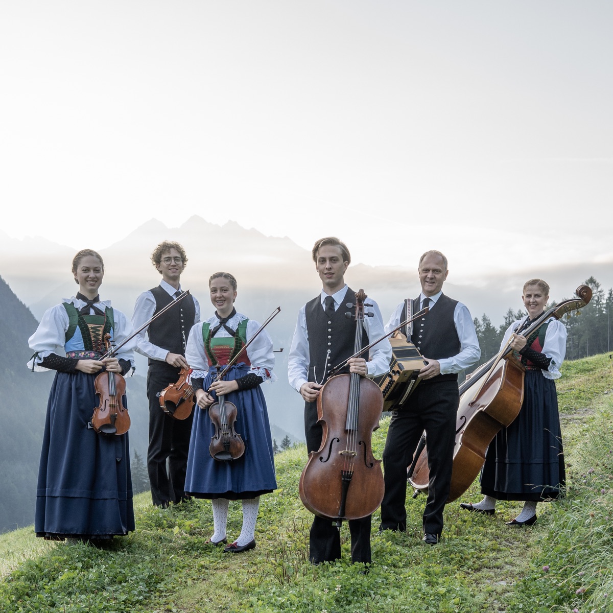Familienmusik Huber in Tracht mit ihren Instrumenten vor einer Berglandschaft