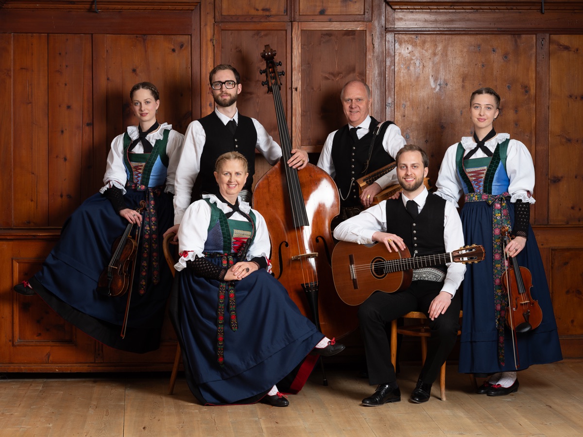 Familienmusik Huber in Tracht mit ihren Instrumenten vor einer Holzwand
